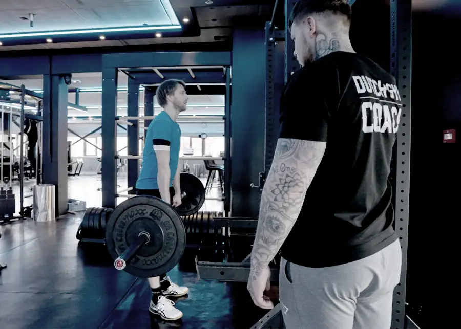 personal trainer coached een client tijdens een deadlift